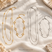 Silver-tone long oval station necklace and short open clover necklace displayed on ivory linen. Each necklace sold separately.