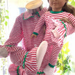 Dolls wearing red and white striped pajamas with green trim against a blurred natural background