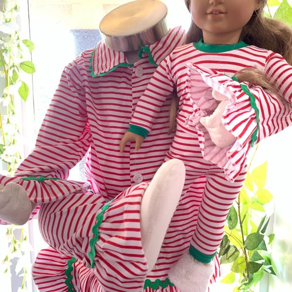 Dolls wearing red and white striped pajamas with green trim against a blurred natural background