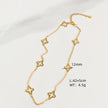 Gold-tone open quatrefoil clover station necklace with extender displayed on ivory linen.