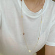 Gold-tone open quatrefoil clover station necklace with extender displayed on ivory linen