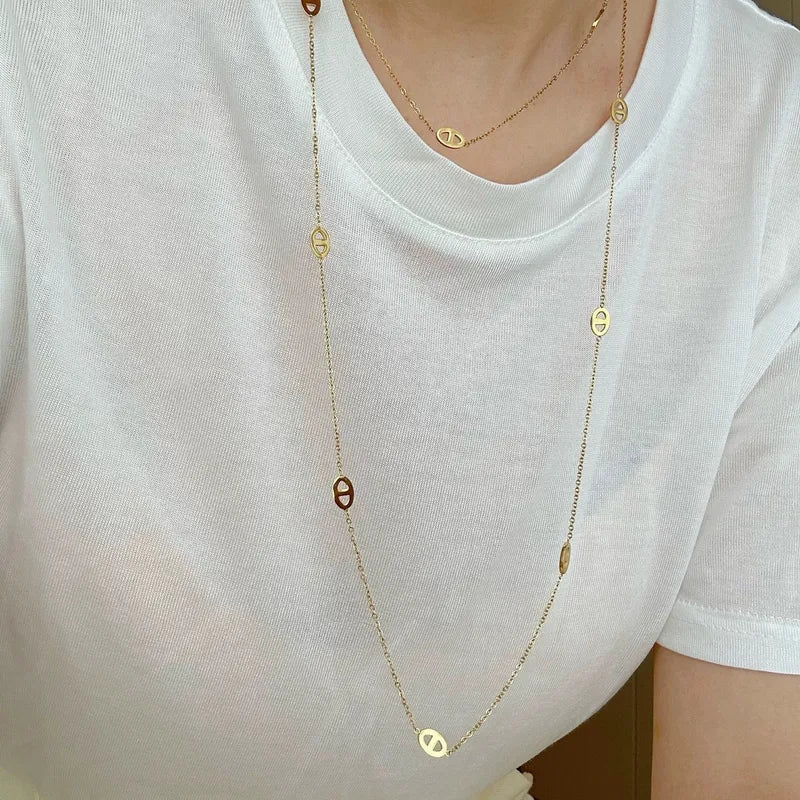 Gold-tone open quatrefoil clover station necklace with extender displayed on ivory linen