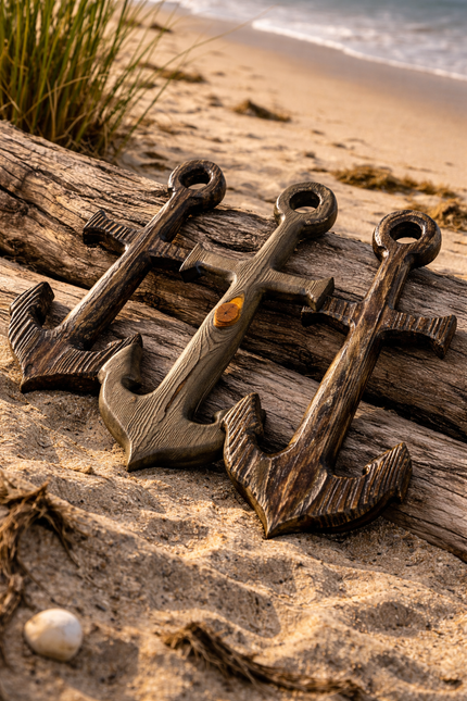 Wooden anchor-shaped objects on a beach with sand and sea foam in the background