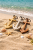 Three wooden anchors on a sandy beach with ocean waves in the background