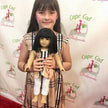 Young girl holding a doll with a branded backdrop