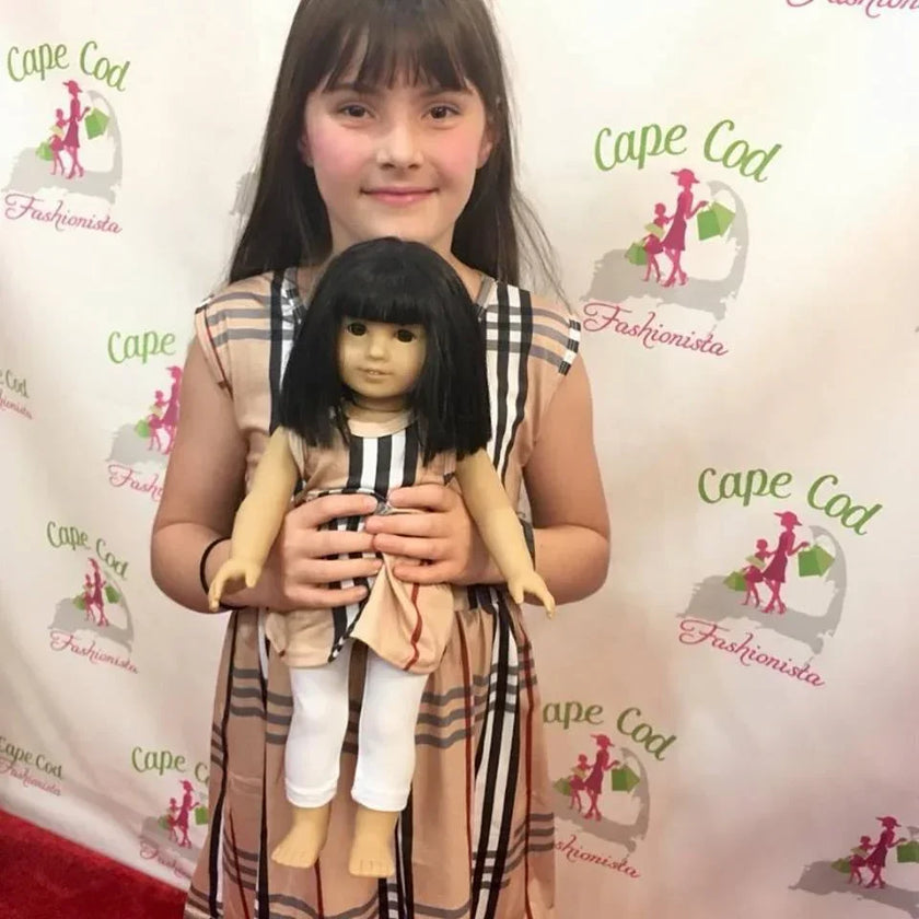 Young girl holding a doll with a branded backdrop