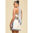 Woman wearing a white outfit with blue patterns on a beige background