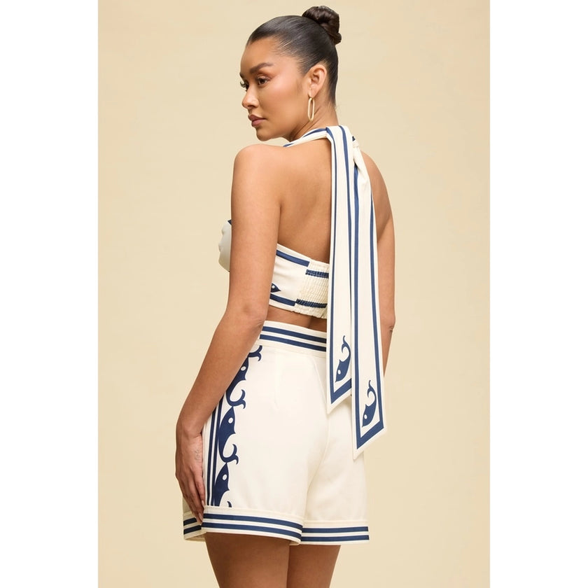Woman wearing a white outfit with blue patterns on a beige background